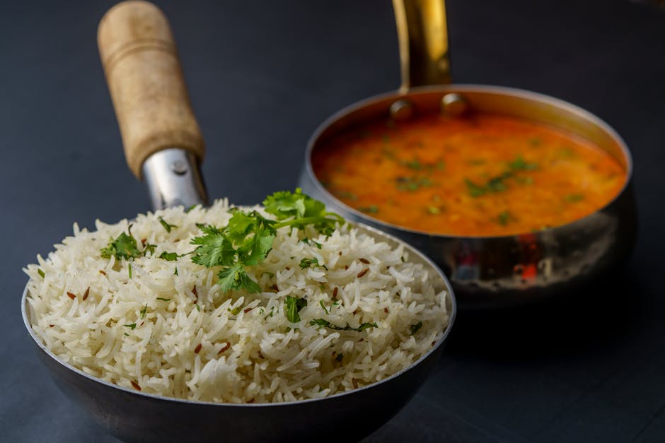 A savory dish of Indian dal with aromatic rice garnished with fresh cilantro, served in traditional utensils.