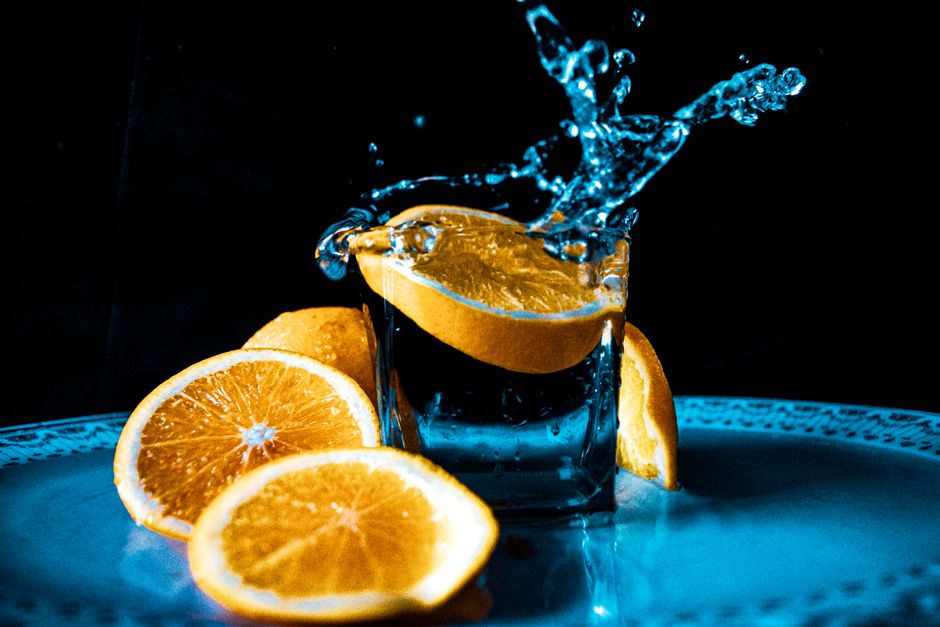 Vibrant orange slices creating a splash in a glass of water, a refreshing and dynamic scene.