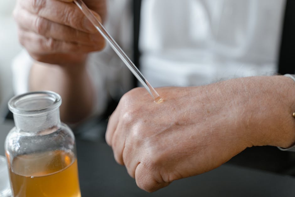 Close-up of a person applying perfume on their hand with a dropper, showcasing the art of fragrance testing.