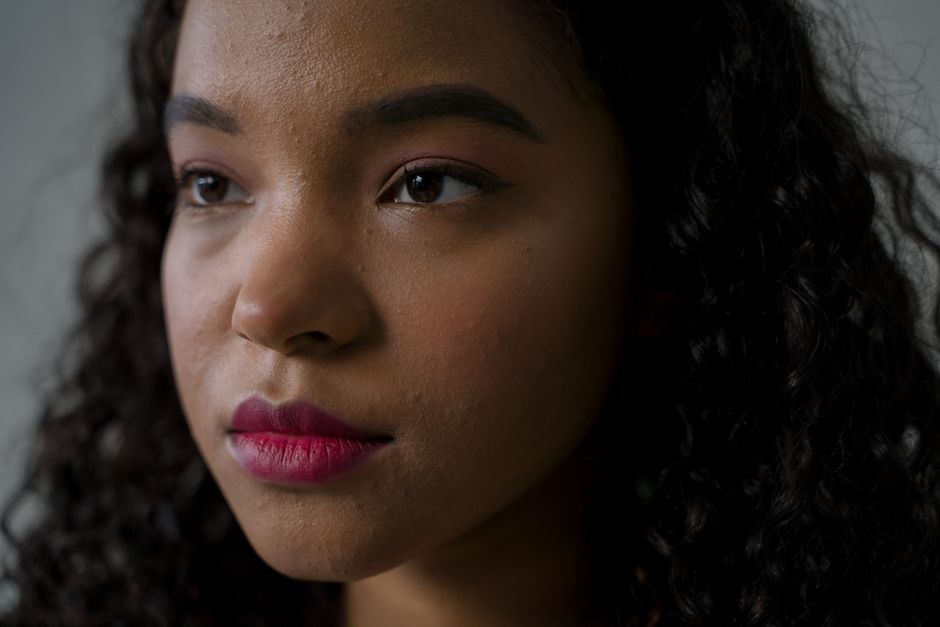 Intimate close-up portrait of a woman with curly hair looking contemplative.