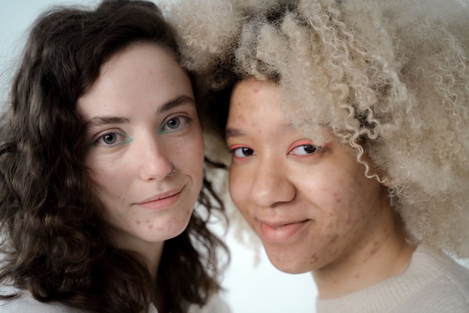Close-up portrait of two diverse women with natural makeup, embracing self-confidence.