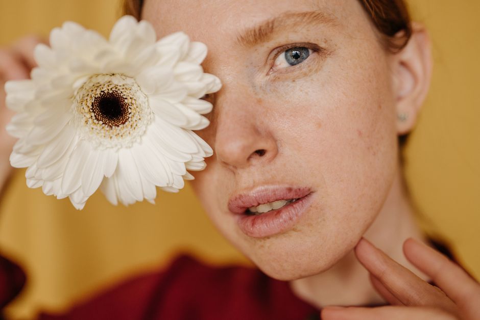 Close-up portrait of a woman holding a white dahlia, emphasizing natural beauty.