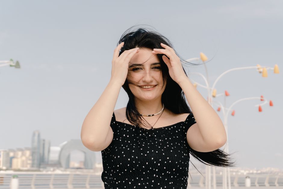 A woman smiles with cityscape background on a breezy day in Baku, Azerbaijan.