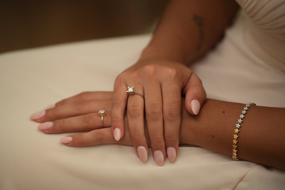 A close-up photo showcasing elegant manicured hands adorned with rings and a bracelet.