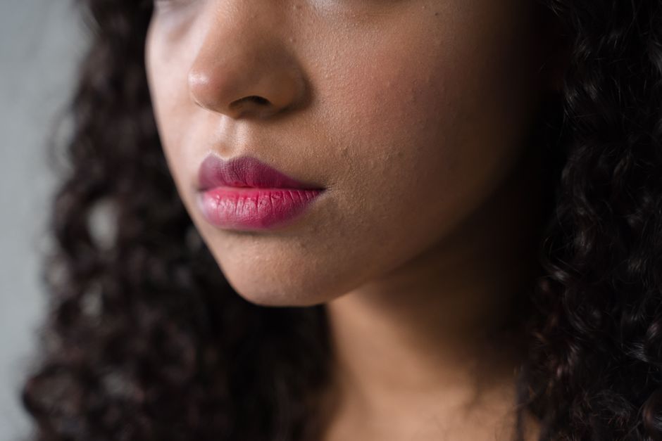 Intimate close-up of a woman's face emphasizing textured lips and skin tone.