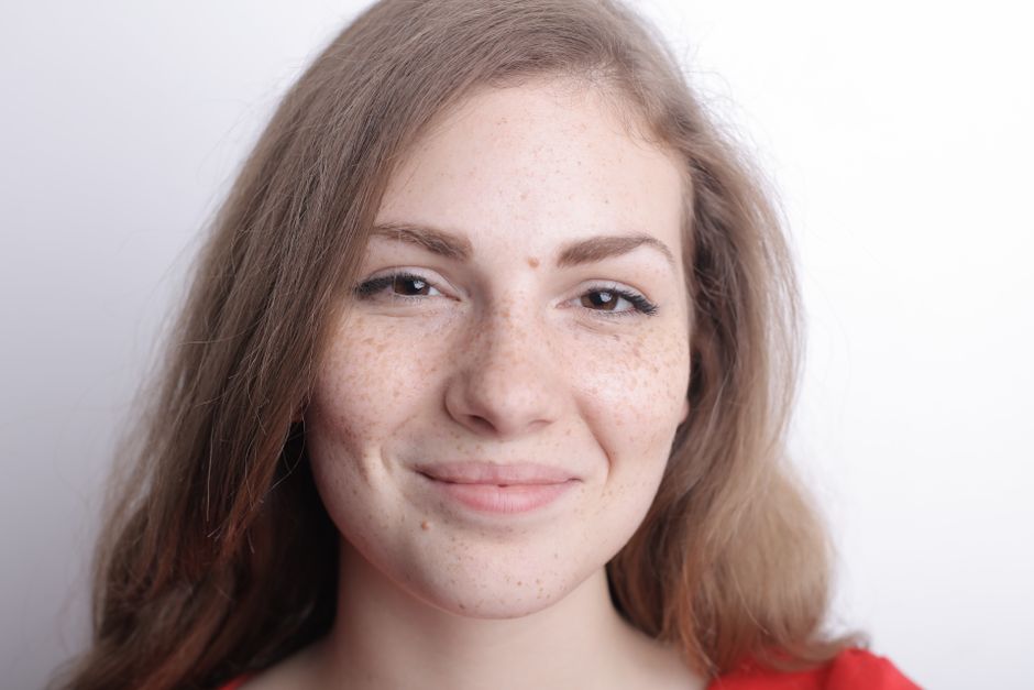 Close-up portrait of a smiling young woman with freckles and natural beauty.