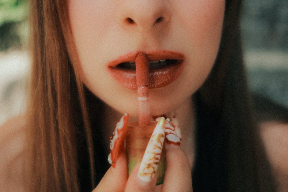 A woman applies lipstick, showcasing detailed nail art in an outdoor setting in Istanbul.