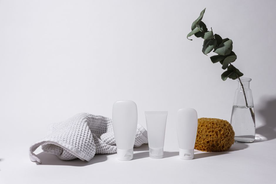 Simple and clean spa arrangement with white bottles, towel, and eucalyptus in vase.