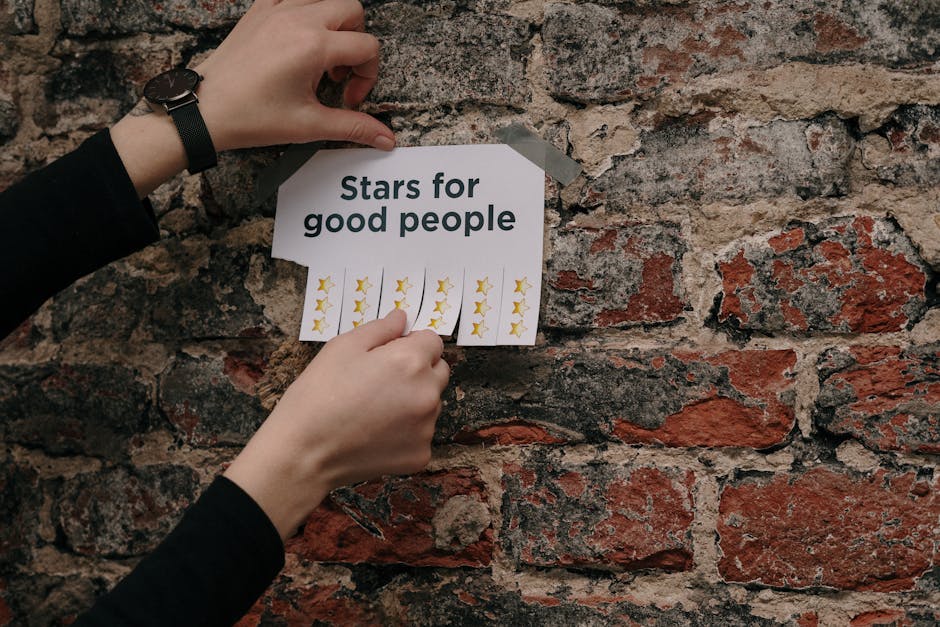 Close-up of hands taping a motivational paper with stars on a rustic brick wall.