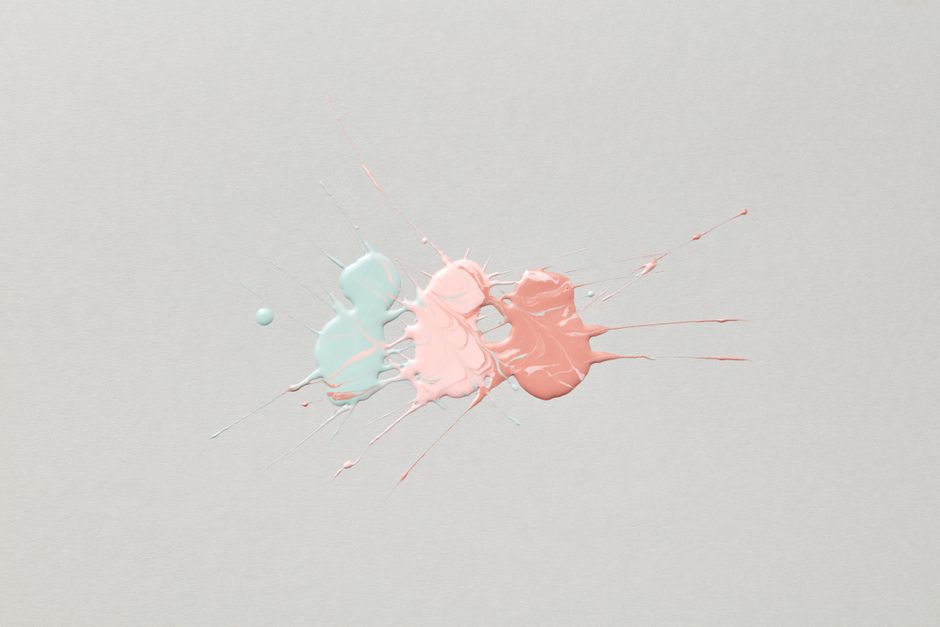 Colorful splatter of blue and pink paint on a white surface, artistic expression.