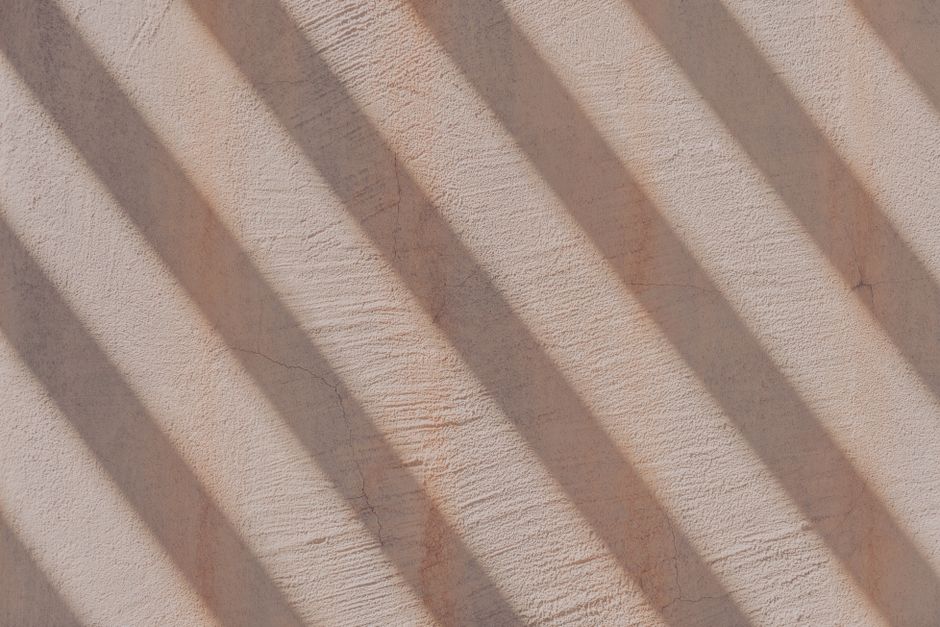 Close-up of a sunlit wall casting diagonal shadow patterns, creating a striking visual texture.