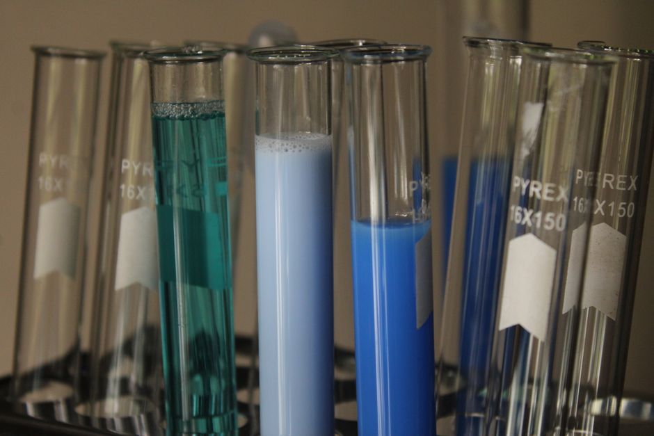 Close-up of colorful chemical solutions in glass test tubes in a laboratory setting.