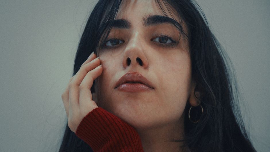 Close-up portrait of a woman in a red sweater, exuding elegance and sophistication.