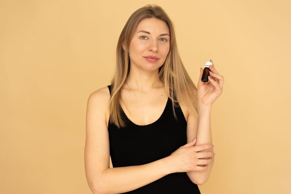 Confident young woman holding skincare serum bottle, promoting beauty and wellness.