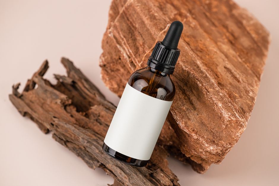 Minimalist image of a brown dropper bottle with a blank label on rustic wood, ideal for natural products.
