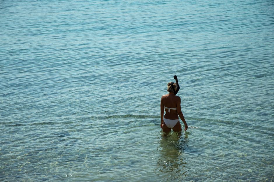 Young woman snorkeling in crystal clear sea waters during summer vacation.