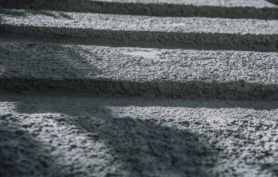 Close-up view of rough textured concrete with shadows, creating an abstract pattern.