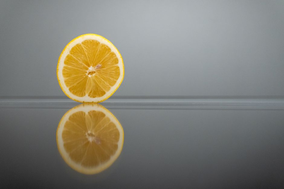 A fresh lemon slice on a reflective surface, showcasing vibrant colors and textures.