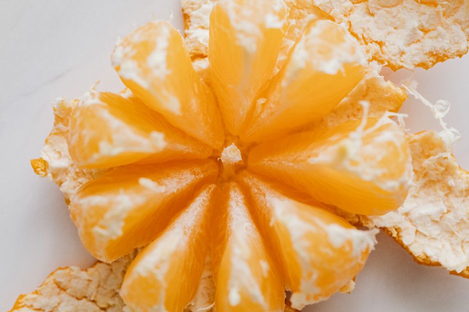 An artistic close-up of juicy orange segments surrounded by peel on a white surface.